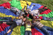 Kinder liegen auf Fallschirm